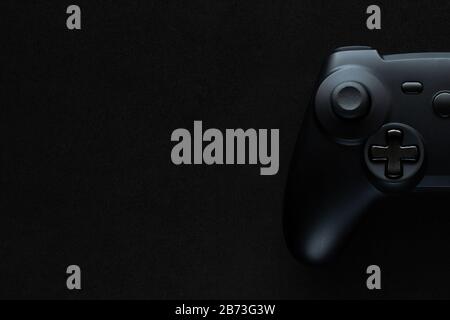 Stock photo of a black gamepad on a textured black background and copy space on the left Stock Photo