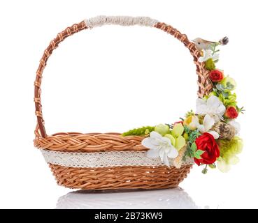 Brown wicker basket with original handle. Decor with flowers, eggs and a small ceramic bird. Made in a rustic style. Isolated on a white background Stock Photo