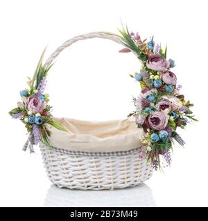 Wicker basket with flowers and ribbons. Beautiful floral decor on the side on the basket handle. Isolated Stock Photo