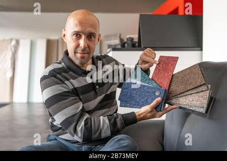 The man selects a new cover for the sofa from the color card sampler Stock Photo