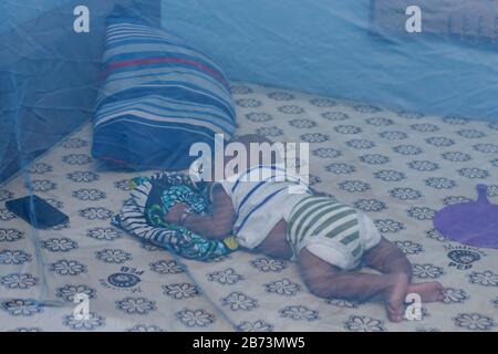New born child sleeping under mosquito net, concept provides mosquito nets to protect children from dengue Stock Photo