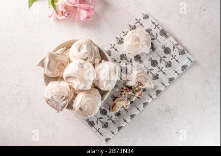 Homemade eggs dessert meringue on a plate on a light background. Next to pink flower and pieces of cookies. Copy space Stock Photo