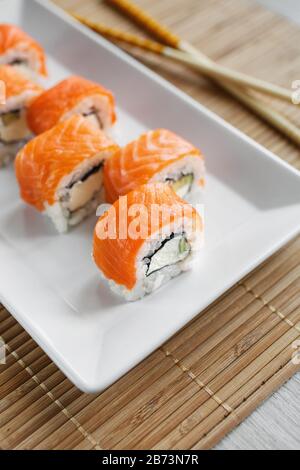 Traditional fresh Japanese sushi rolls with salmon on a white plate.