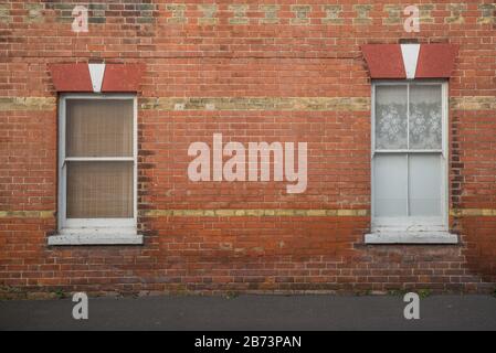 two (2) windows on a red brick wall with sand coloured brick detail. Stock Photo
