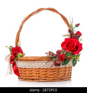 Decorated natural vine basket with high handle. Decor of red roses and lace ribbon on white background Stock Photo