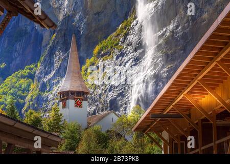 Autumn view of Lauterbrunnen Staubbach Falls waterfall and church tower in Swiss Alps, Jungfrau region, Switzerland Stock Photo