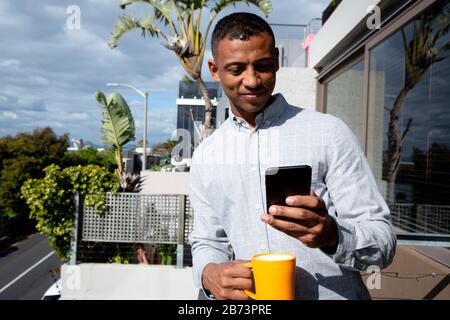 Man using his phone and drinking coffee Stock Photo