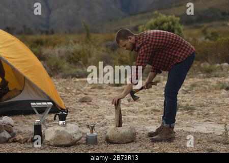 Side view of man chopping wood with an ax Stock Photo