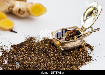 Dry tea herbs with spices in vintage silver and fresh ginger root on white background. Stock Photo