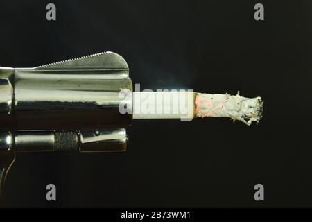 Cigarette fire in gun muzzle compared smoking can kills Stock Photo