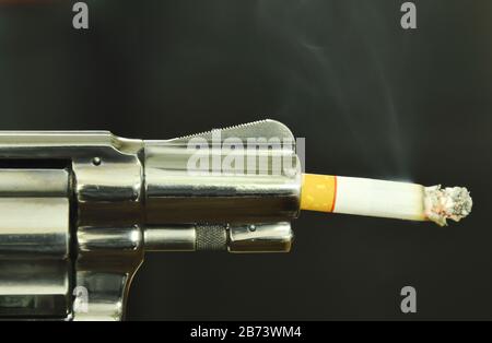 Cigarette fire in gun muzzle compared smoking can kills Stock Photo