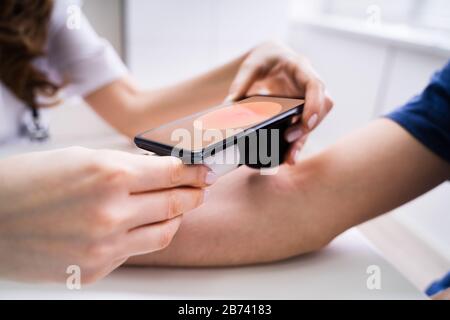 Female Doctor Examining Pigmented Skin Of Male Patient Stock Photo