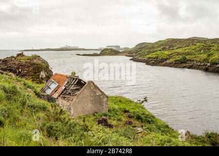 An abandoned cottage on the shore of Stornoway Bay, in the grounds of Lews Castle, Stornoway, Scotland, UK.  Cunard ship Queen Eliszabeth can be seen. Stock Photo