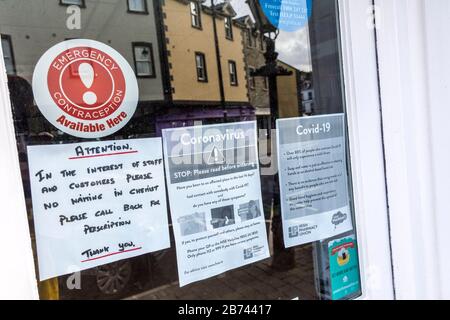 Ardara, County Donegal, Ireland. 13th March 2020. Advice notice for customers not to wait inside the chemists pharmacy shop whilst obtaining prescriptions to  help prevent spread of Coronavirus, Covid-19, as infections increase throughout the Republic. Stock Photo