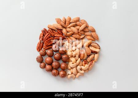 Assorted brown nuts on a gray background. Macadamia, cashews, chopped almonds, pecans healthy food Stock Photo