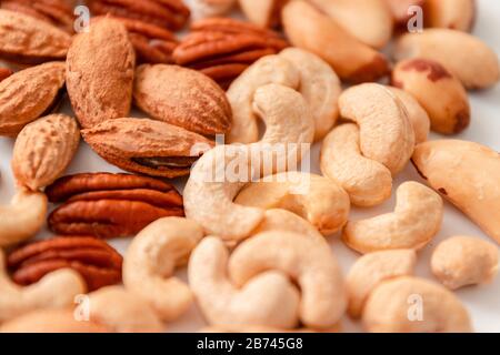 Close up assorted brown nuts on a gray background. Macadamia, cashews, minced almonds, pecans, wholesome food Stock Photo