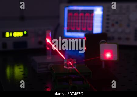 Experiment in optic lab with laser device. Red laser on optical table in physics laboratory Stock Photo