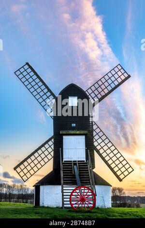 After a dry day with intermittent sunshine and a strong breeze in Ivinghoe, Buckinghamshire, the sun sets behind the famous Pitstone Windmill on the R Stock Photo