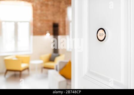 Round smart thermostat with touch screen installed on the wall indoors. Smart home heating regulation concept Stock Photo