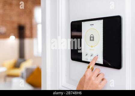 Controlling home alarm system with a digital touch screen panel installed on the wall. Concept of wireless secure control and smart home Stock Photo