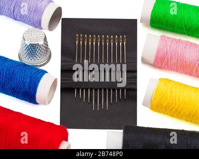 Set of steel sewing needles with golden needle's eyes, threads of different colors isolated on white background Stock Photo