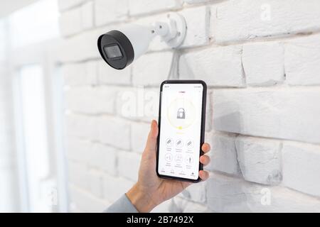 Controlling video surveillance and home alarm with mobile application, close-up on a smart phone with launched app. Concept of a wireless home security systems Stock Photo