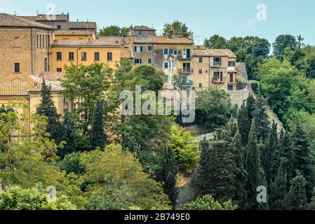Residential houses of the old town built on a steep slope in a popular hilltop town of Volterra, Tuscany, Italy, seen from Piazza XX Settembre in May. Stock Photo