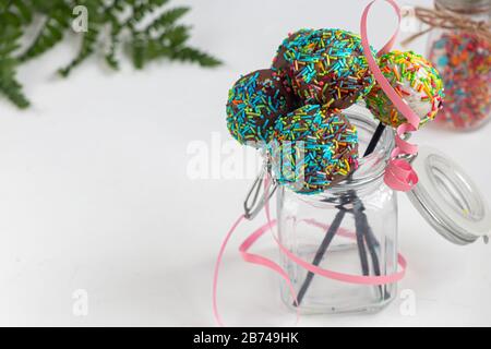 A colorful cake pops up, lying on a table. It is covered with sweet multi-colored sweets. Copy space Stock Photo