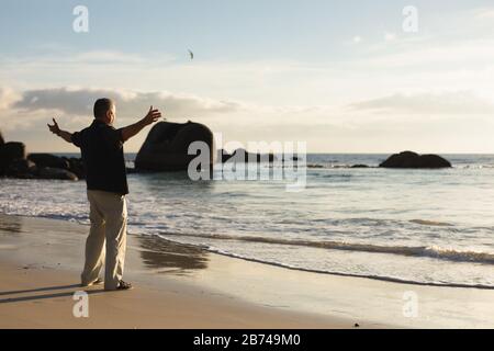 Senior man raising arms on seaside Stock Photo