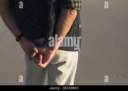Senior man hands behind back on seaside Stock Photo