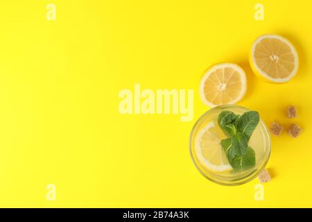 Lemonade, lemons and sugar cubes on yellow background, space for text Stock Photo