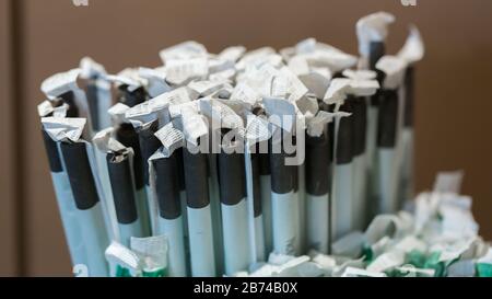 Close up of drinking straws wrapped in paper. Black and white color. Used for hot (e. g. latte macchiato) and cold drinks (e. g. lemonade). Stock Photo