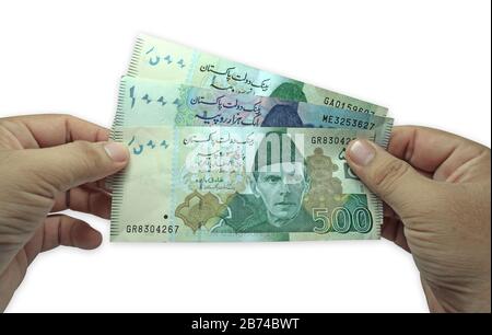 Brown man holding multiple Pakistani currency notes on white background Stock Photo