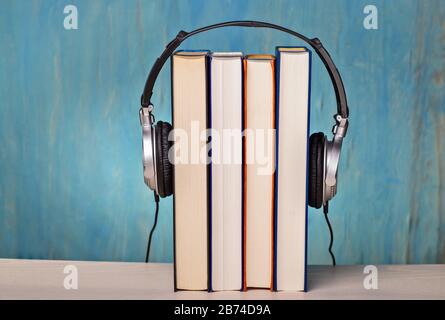 Headphones with four books as symbol for audio books | usage worldwide Stock Photo