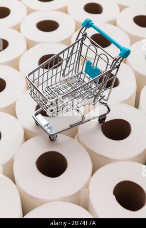 Supermarket shopping trolly on a background of toilet paper rolls Stock Photo