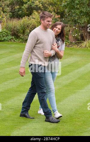 Pregnant young woman walking with her partner arm in arm Stock Photo