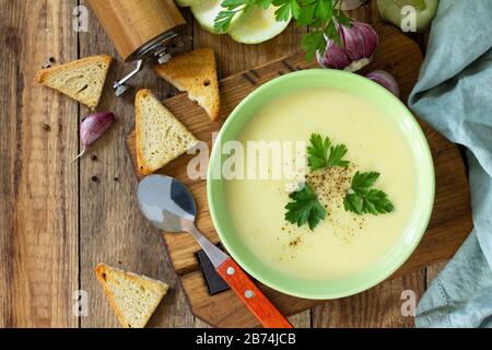 The concept of healthy and diet food, vegetarian dish. Delicious vegetable soup with cream and zucchini on a rustic table. Top view flat lay backgroun Stock Photo