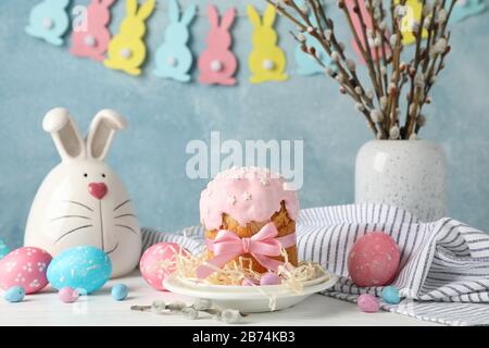 Easter composition with Easter cake and eggs on white wooden table against blue background Stock Photo