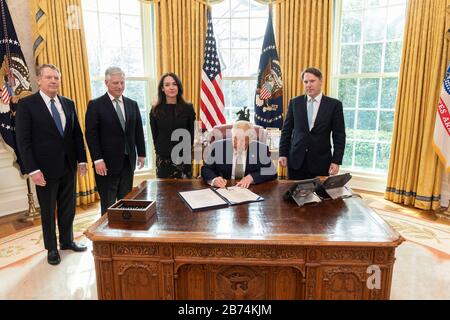 Washington, United States of America. 12 March, 2020. U.S President Donald Trump signs H.R. 4998, the Secure and Trusted Communications Networks Act of 2019 in the Oval Office of the White House March 12, 2020 in Washington, DC. Standing around the president from left to right are: Trade Representative Amb. Robert Lighthizer, National Security Advisor Amb. Robert O'Brien, Special Assistant to the President for Economic Policy Robin Colwel and Presidential Assistant and Special Representative for International Telecommunications Policy Robert Blair. Credit: Shealah Craighead/White House Photo Stock Photo