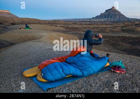 Mylène Jacquemart and Robert Hahn take pictures of Factory Butte at sunrise from camp in the badlands of Factory Butte Recreation Area near Caineville Stock Photo