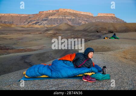 Mylène Jacquemart and Robert Hahn watch sunrise from camp in the badlands of Factory Butte Recreation Area near Caineville, Utah. North Caineville Mes Stock Photo
