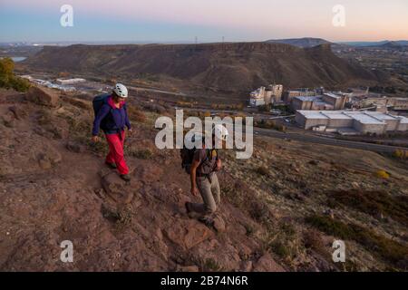 Mylène Jacquemart and Obadiah Reid walk down the access trail to Golden Cliffs on North Table Mountain, above Golden, Colorado. The Coors Brewery is v Stock Photo