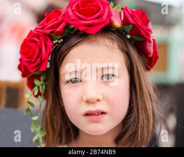 Beautiful little girl in a wreath on the head in green and white. Party ...