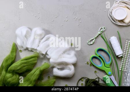 A set of items for needlework makes snowdrops from wool on a gray work surface, shot with a large fragment. Stock Photo