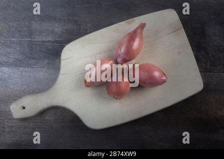 studio shot of onions shallot one whole and some sliced  on cutting desk Stock Photo
