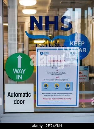 Western General Hospital, Edinburgh, Scotland, United Kingdom. 13th Mar, 2020. Coronavirus warning temporary sign on the entrance doors to an out patient wing on the day that the first person dies from Covid-19 in Scotland in Lothian during the infection pandemic Stock Photo