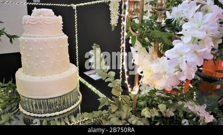 White wedding cake with flowers. Big wedding cake. Decor trends. Wedding ceremony. On the black background. Stock Photo