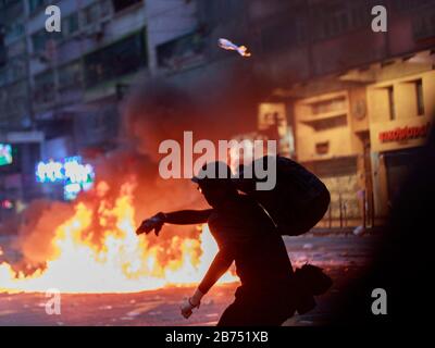 A protester set a street on fire to stop police from advancing. Protesters clash with anti-riot police in Hong Kong during China's 70th anniversary. Stock Photo