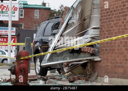 Ontario, Canada 2020: Close up of car accident involving SUV collision with brick building. Emergency units investigate vehicle accident. Stock Photo