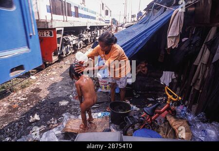 10.08.2009, Jakarta, Java, Indonesia, Asia - A mother is washing her child next to the railway tracks in a slum area of the Indonesian capital. [automated translation] Stock Photo